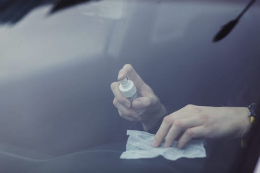 the driver cleans the car interior with an alcohol-based antibacterial spray. protection against the spread of coronovirus infection
