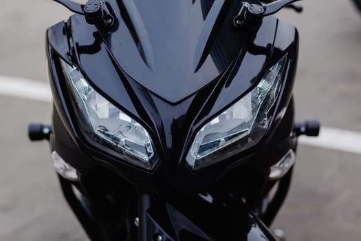 close-up of the headlights of a black sports motorcycle on the street.