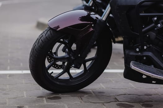 black wheel of a sports motorcycle standing on the asphalt.