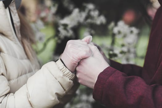 two lovers holding hands in gloves. protection from coronavirus