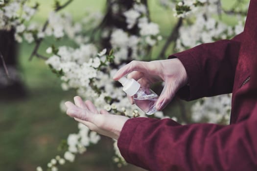 Hand of man that applying alcohol spray or anti bacteria spray to prevent spread of germs and virus outdoors. Personal hygiene concept.