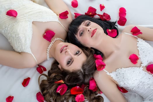 Top view of beautiful dark-haired brides lying in bed