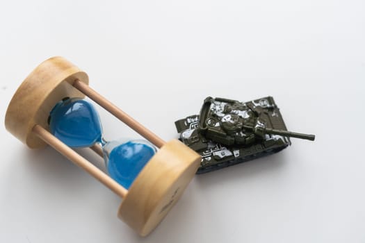 The plastic tank toys on the floor next to an hourglass. High quality photo