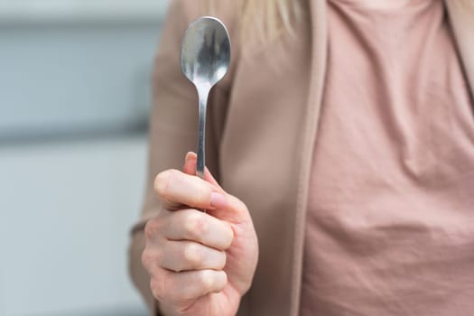 Metallic empty eating spoon in a human right hand with clipping path isolated on white. High quality photo