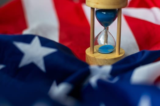 Hourglass and USA flag, soft focus, copy space. High quality photo