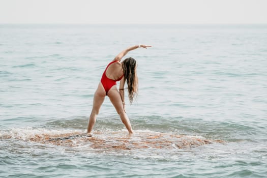 Woman sea yoga. Back view of free calm happy satisfied woman with long hair standing on top rock with yoga position against of sky by the sea. Healthy lifestyle outdoors in nature, fitness concept.