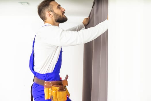 Man hanging window curtain indoors, closeup. Interior decor element.