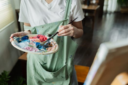 A beautiful young woman artist working on painting something on a large canvas.