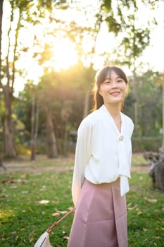 Portrait of smiling businesswoman walking on tropical park and looking away.