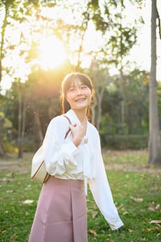 Young beautiful businesswoman walking in the public park on sunny summer day.