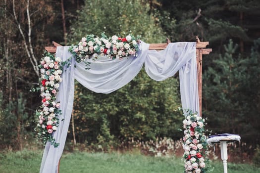 Beautiful wedding ceremony outdoors. Wedding arch made of cloth and flowers
