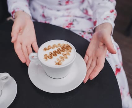 Female hands in dress holding cup of coffee. Close up