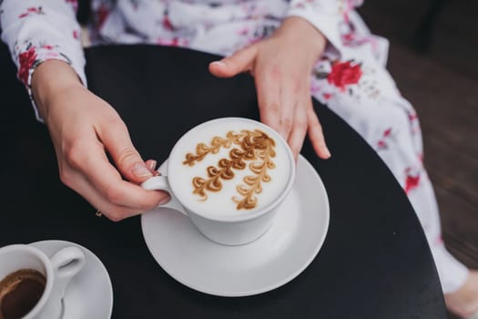 Female hands holding a cup of coffee with over table, top view