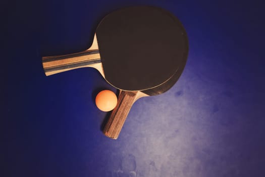 Blue table tennis or ping pong. Two table tennis or ping pong rackets or paddles and ball on a blue table