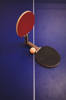 two tennis rackets and a ball on the table. ping pong