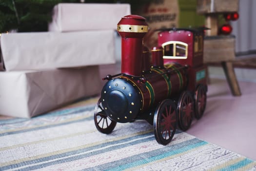 toy vintage steam locomotive on the floor under a decorated Christmas tree