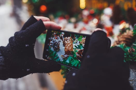close-up of the hands of a tourist with a smartphone taking a photo of the Christmas decor