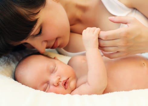 Happy mother and infant sweet sleeping lying on white bed at home