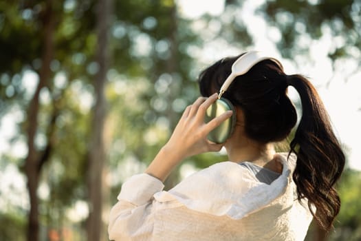 Happy relaxed young lady listening to music with headphones in nature.