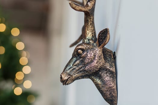 decorative deer head hanging on the wall against the background of Christmas lights