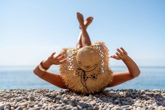 Beach Relaxation woman lies on a pebble beach, legs raised, and arms spread out. The concept of travel, vacation at sea.