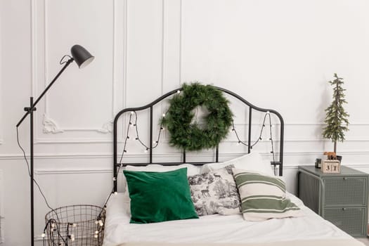 Bedroom interior with bed decorated Christmas tree, gifts, plaid and pillows.