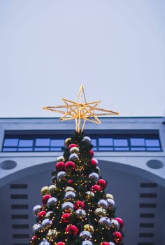 decorated Christmas tree with a star on the background of buildings