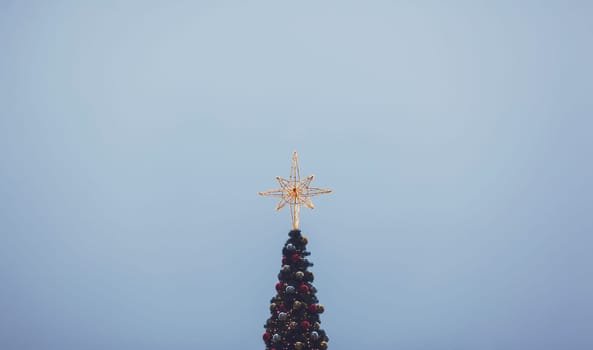 Christmas tree with shining star on sky background; copy space
