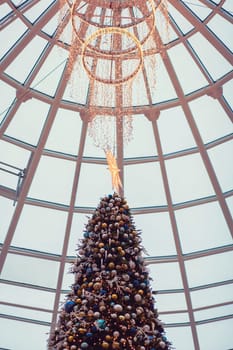 Christmas tree with colorful balls and a star in the shopping center
