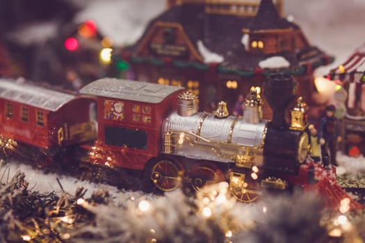 toy vintage steam locomotive decorated Christmas tree on a background of bokeh lights garland. Christmas and New year celebration concept