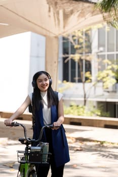 Eco friendly, Happy lifestyle asian beautiful young businesswoman riding bicycle go to office work at city street with bicycle in morning.