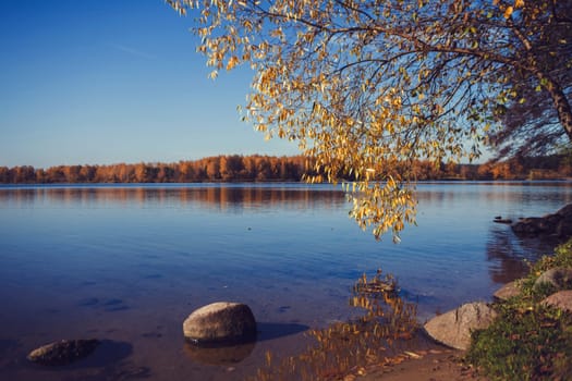 beautiful autumn landscape. rocks on the lake against the blue sky