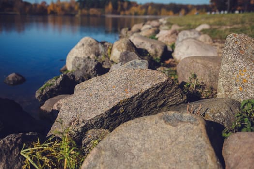 large stones on the background of the river in the autumn park