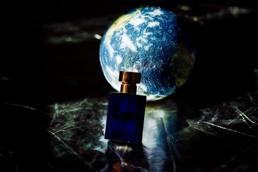 perfume in a blue bottle on the background of a mock-up of the earth. ecological concept. caring for the planet