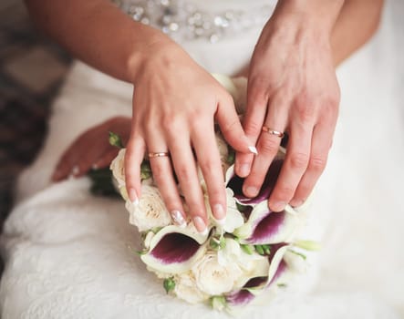 hands of the bride and groom with rings on the background of the wedding bouquet