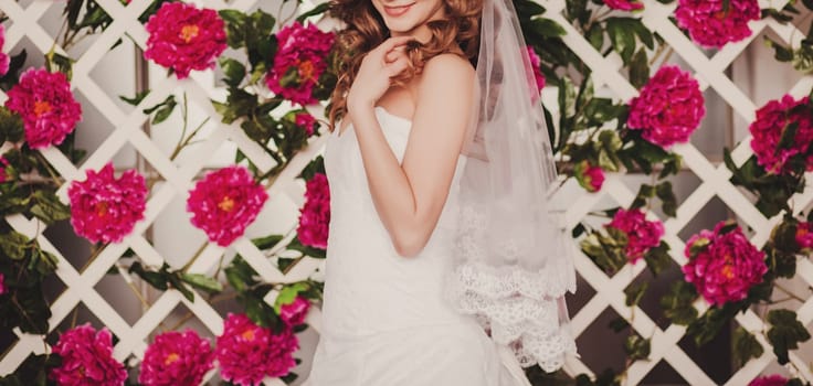 beautiful bride in a wedding dress with lace on the background of a floral arrangement