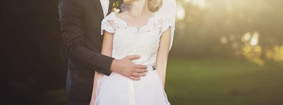 romantic wedding couple embracing at sunset in meadow