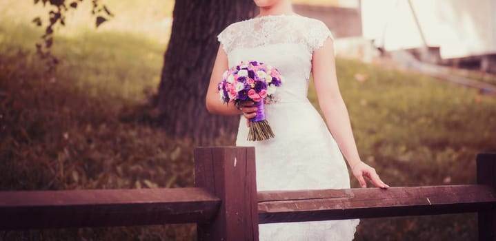 bride in lace wedding dress with bouquet color outdoors
