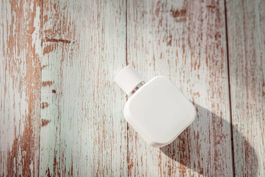 white perfume bottle on wooden textured background. Summer scent concept for vacation