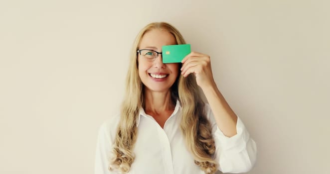 Portrait of happy successful smiling middle-aged woman holding plastic credit bank card on studio white background