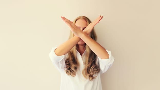 Upset young woman shows stop, no or enough sign with palm of hand, refusal gesture, domestic violence