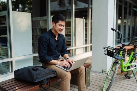 business man sitting on bench and working remotely on project with laptop.