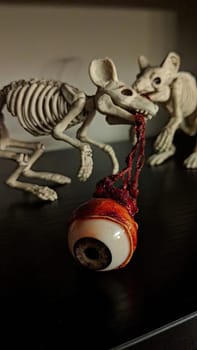 Surreal Macabre Display with Skeletal Rodents and Ominous Eyeball Against Dark Background