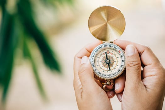 Close-up shot of a woman holding a compass during her forest hike. The compass symbolizes guidance and exploration in the great outdoors.