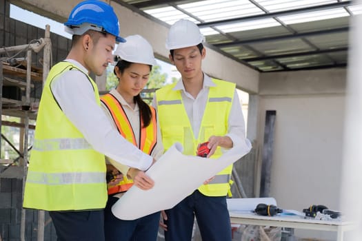 Civil engineer teams meeting working together wear worker helmets hardhat on construction site in modern city. Foreman industry project manager engineer teamwork. Asian industry professional team.