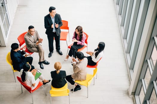 Top view captures a diverse group in a busy office, collaborating and engaged in discussions. A businessman and businesswoman sit at a conference, allowing for your business meeting concept.