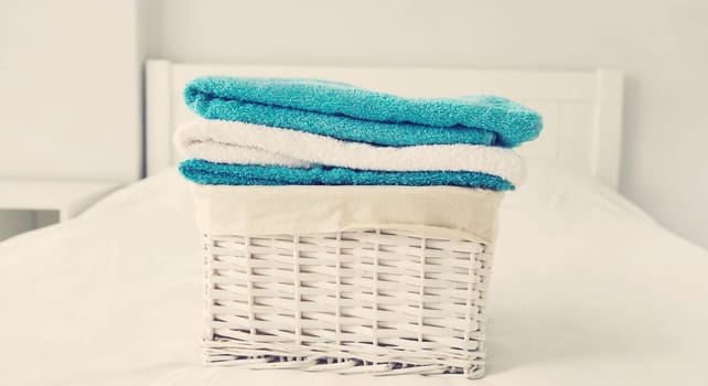 Wicker laundry basket with clean folded towels on the bed