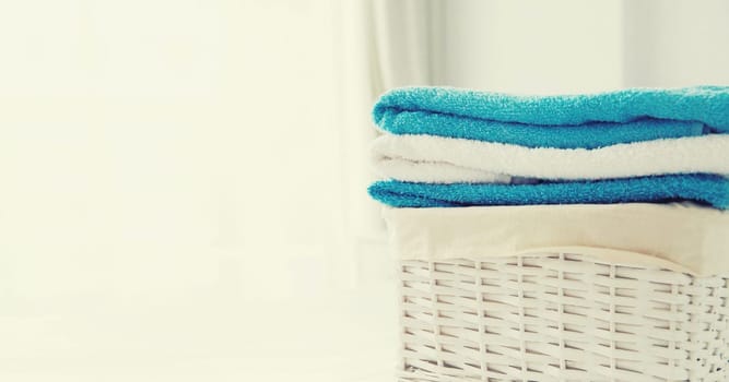 Wicker laundry basket with clean folded towels on the bed