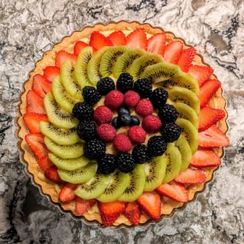 Top view of a vibrant, gourmet fruit tart on a marble surface, showcasing culinary art and healthy eating