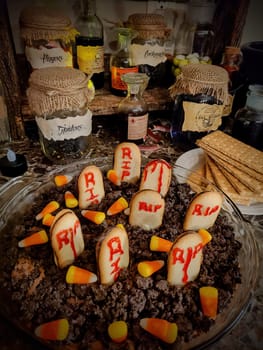 Halloween party setup in Fort Wayne, Indiana with creative home-cooked treats resembling a graveyard and a whimsical witch's pantry, 2021